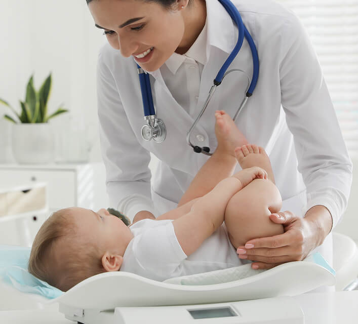 Young Pediatrician Weighting Cute Little Baby Clinic